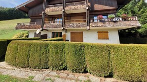A two-story chalet with a wooden balcony, a satellite dish, and a well-maintained hedge in front. - 3-room apartment with garage, 6 sleeps in Grand-Bornand (Le Grand-Bornand)