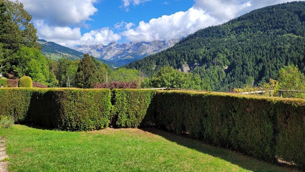 A well-maintained garden with neatly trimmed hedges and a clear view of a mountainous landscape in the background. - 3-room apartment with garage, 6 sleeps in Grand-Bornand (Le Grand-Bornand)