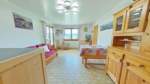 A cozy, well-lit room with a wooden floor, a sofa, a dining table set with plates and glasses, and wooden cabinets. - 3-room apartment with garage, 6 sleeps in Grand-Bornand (Le Grand-Bornand)