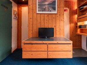 A wooden cabinet with a flat-screen TV, a framed picture above it, and a blue carpeted floor.