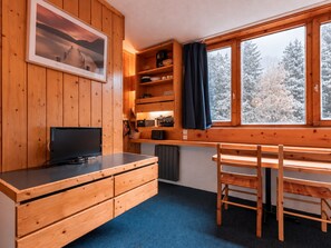 A wooden cabin interior with a television, wooden cabinets, a desk, and a window overlooking a snowy landscape. - Cozy studio Arc 1800, 2 people, Wifi, pets allowed (Les Arcs 1800)