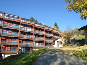 A multi-story building with balconies, a paved driveway, and a mountainous backdrop. - Cozy studio Arc 1800, 2 people, Wifi, pets allowed (Les Arcs 1800)