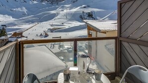 A snow-covered mountain landscape with a ski slope and a building with a roof.