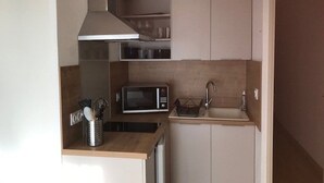 A compact kitchen with a microwave, sink, and a range hood.
