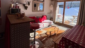 A cozy living room with a sofa, a dining table, and a kitchen area with a microwave. - D104 - 42 m2 - 2P+cab - 4/6 pers (Prapoutel)