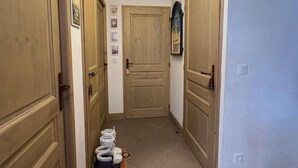 A hallway with wooden doors, a light fixture, and a rug with shoes. - D104 - 42 m2 - 2P+cab - 4/6 pers (Prapoutel)