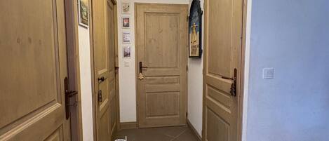 Ein Flur mit Holztüren, einer Lampe und einem Teppich mit Schuhen darauf.
