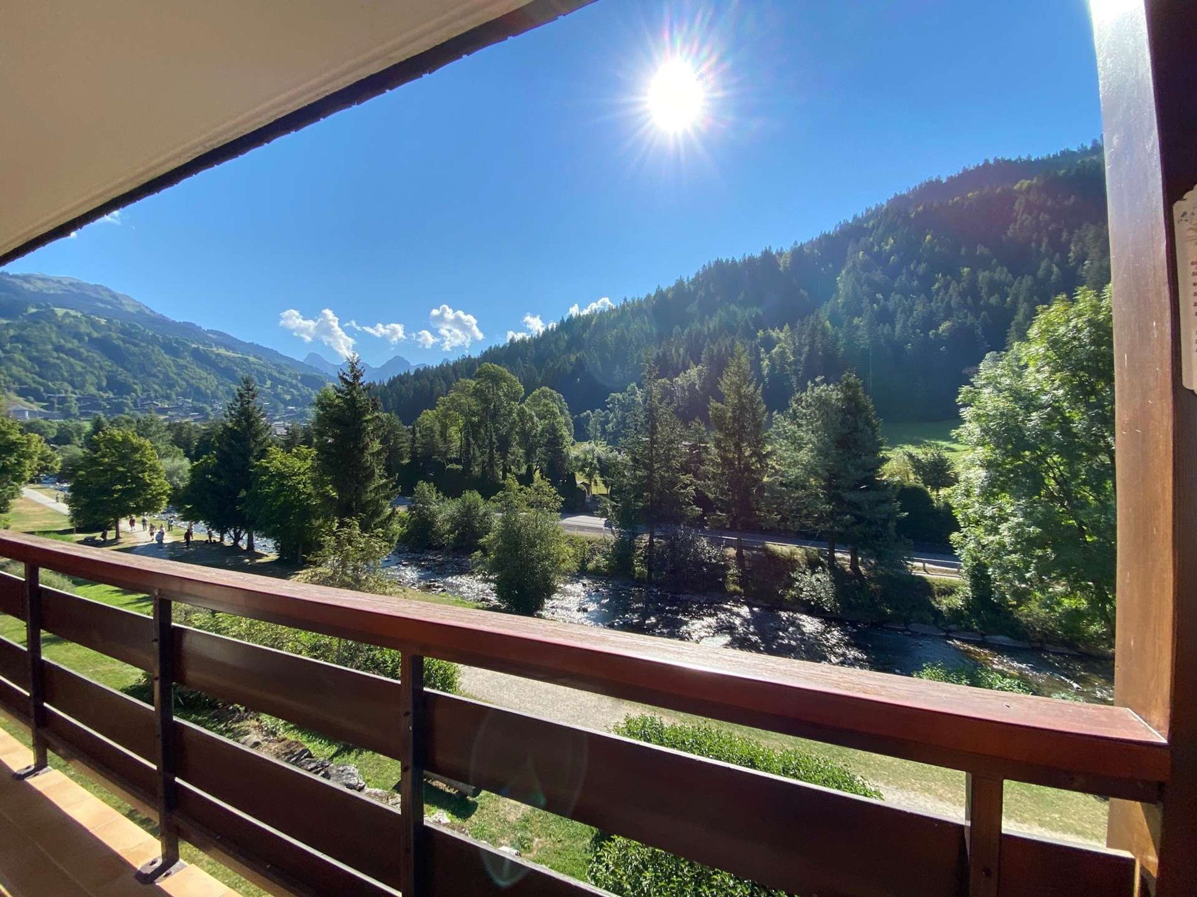 A balcony with a view of a river, forest, and mountains.