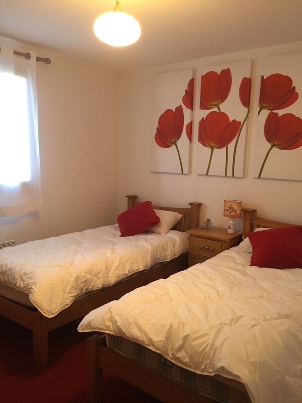 Two single beds with white bedding and red pillows in a room with a wooden headboard. There are wall-mounted paintings of red flowers above the beds. - B103 - 64 m2 - 4P - 6 pers (Prapoutel)