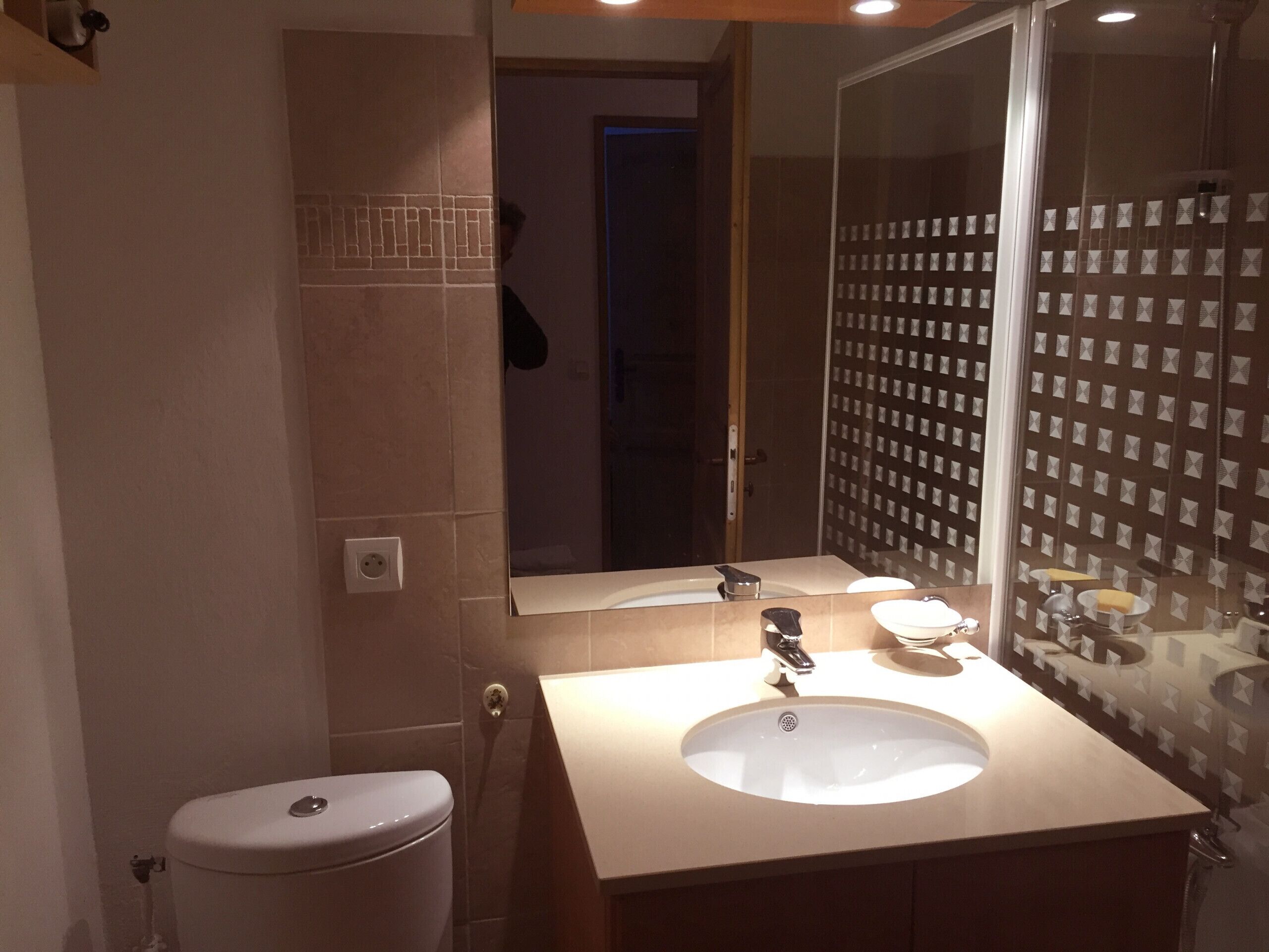A bathroom with a toilet, sink, and mirror.