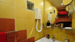 A bathroom with yellow and orange tiles, a white sink, and a mirror above it. - D1GG Colorado (Paris)
