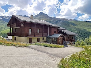 A wooden chalet with a balcony, a small annex, and a mountain view.