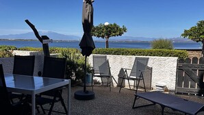 An outdoor patio with a table and chairs, a grill, and a view of the sea and mountains. - Charming T2 Cabin with terrace and pool in Port Barcarès (Port Barcarès)