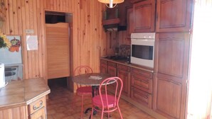 A wooden-paneled kitchen with a dining table and chairs, a stove, and cabinets.
