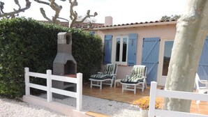 A patio area with a grill, outdoor seating, and a white fence.