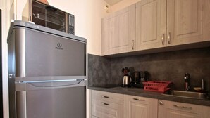 Eine Küche mit einem Edelstahl-Kühlschrank, Holzschränken, einer Arbeitsplatte mit Kaffeemaschine und einem roten Korb.