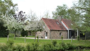 A stone building with a red-tiled roof, a small door, and a chimney.
