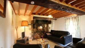 A cozy living room with a stone fireplace, wooden beams, and leather sofas.