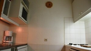Una cocina con gabinetes blancos, una cafetera y un reloj en la pared.
