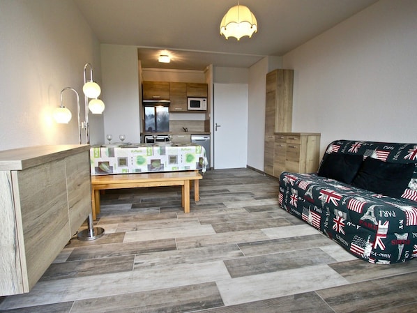 A compact living space with a kitchenette, a dining area, and a sofa with a patterned cover.