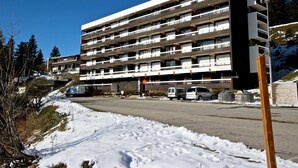 Ett parkeringshus med flera våningar och flera parkeringsplan, omgivet av snötäckt mark och träd.