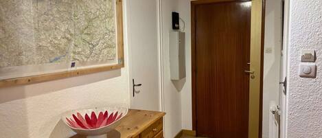 Un pasillo con un armario de madera, un mapa colgado en la pared, una puerta y un radiador.