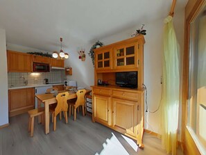 Uma cozinha compacta com armários de madeira, uma mesa de jantar e cadeiras.