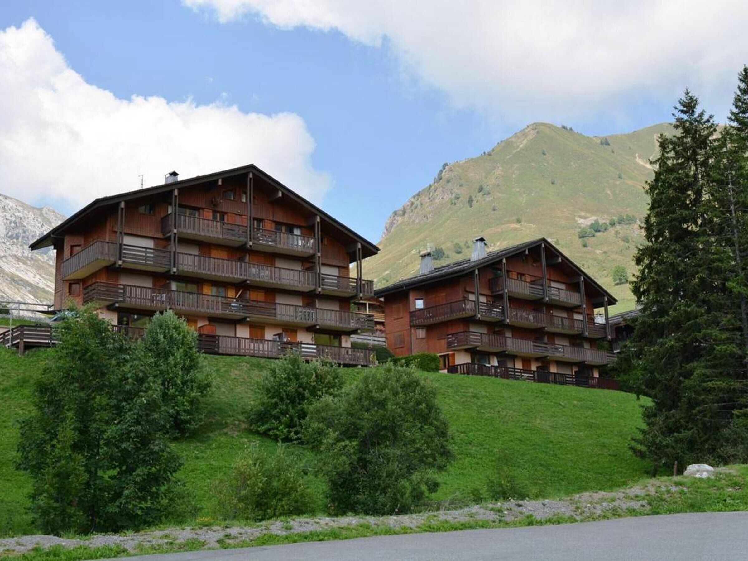 Un chalet de montagne doté de plusieurs balcons et offrant une vue sur les collines environnantes.