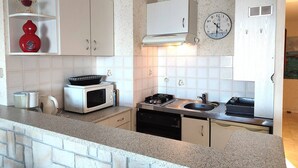 A compact kitchen with white cabinets, a microwave, a stove, and a sink.