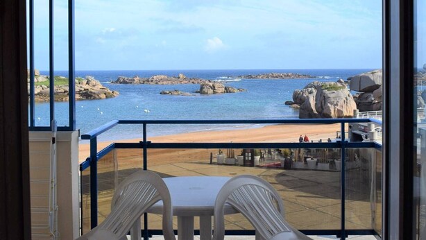 A balcony with a view of the sea and rocky outcrops.