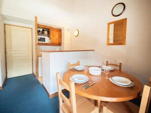 A compact kitchen with wooden cabinets, a microwave, and a dining area with a round table set for four.