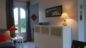 A living room with a sofa, a small table, a cabinet, a lamp, and a painting on the wall. - Charming studio at the Manor with private garden and WiFi (Baubigny)