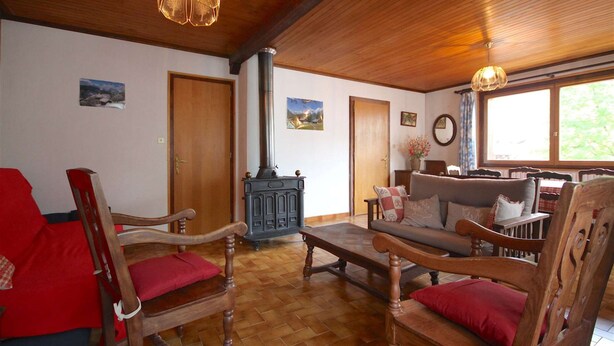 A cozy living room with wooden furniture, a fireplace, and a large window. - Triolets 1 - 3 bedroom apartment in the centre (MORZINE)