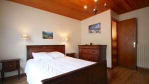 A bedroom with a wooden bed, nightstands, a dresser, and a door. - Triolets 1 - 3 bedroom apartment in the centre (MORZINE)