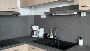 A modern kitchen with a black sink, a coffee maker, and a kettle.