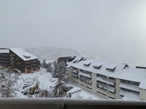 Um edifício coberto de neve com várias varandas e estacionamento com carros cobertos de neve.