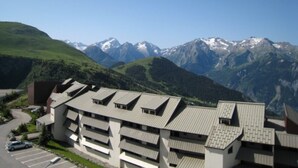 A multi-story hotel with a modern architectural design, located in a mountainous area with a view of snow-capped peaks.