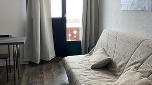 A room with a bed, a table, and a window with curtains.