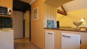 A kitchen with a microwave, a small refrigerator, and a sink. There is a window with a view of the outside.