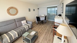 Ein modernes Wohnzimmer mit einem grauen Sofa, einem Couchtisch und einem Essbereich mit Tisch und Stühlen.