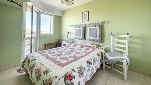 A bedroom with a bed, a chair, a nightstand, a window, and a ceiling light. - 1 Bedroom Apartment + Cabin with Sea & Dune View, 3rd Floor with Elevator (Cucq-Stella Plage)