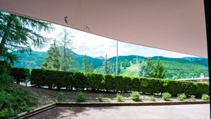 A room with a large window overlooking a mountainous landscape.