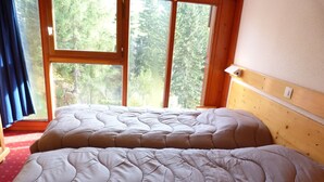 Un dormitorio con dos camas, ventanas amplias y un cabecero de madera.