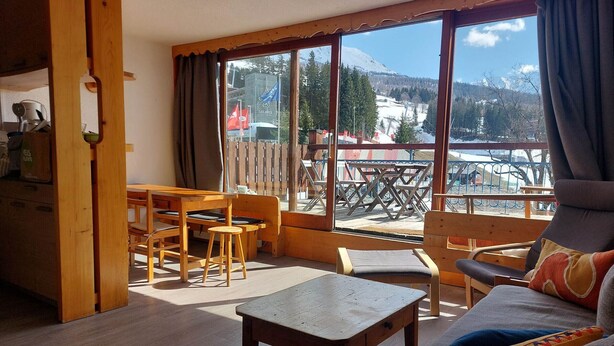 Ett mysigt rum med ett träbord, en soffa och utsikt över ett snötäckt berg.