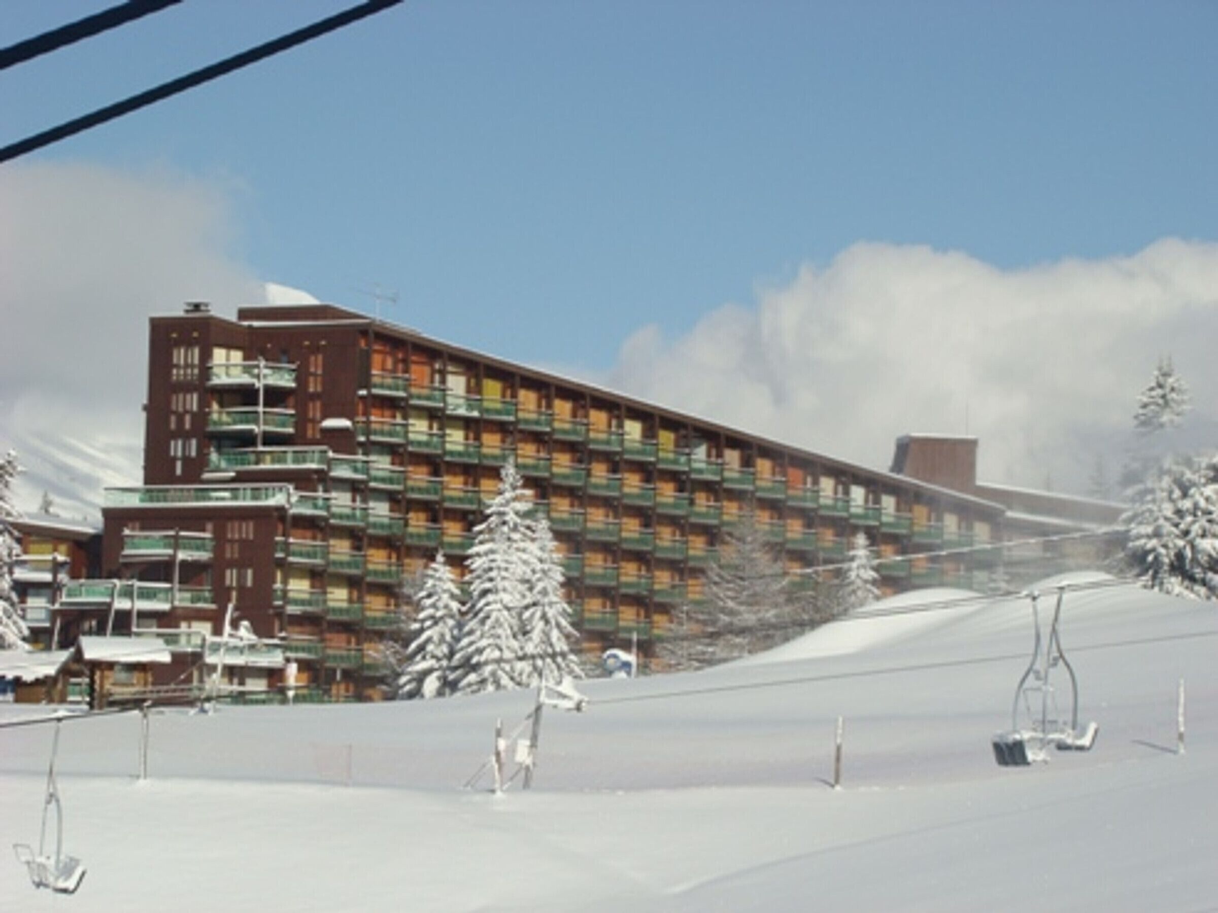A multi-story hotel with balconies, a ski slope, and snow-covered trees.