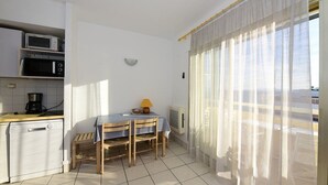 Una cucina compatta con zona pranzo, un forno a microonde, una macchina del caffè e un tavolo con sedie.