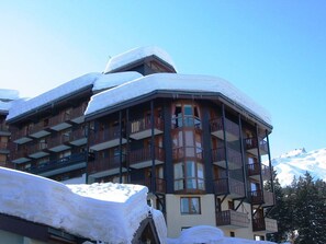 Un hotel de varios pisos con balcones y un techo cubierto de nieve.