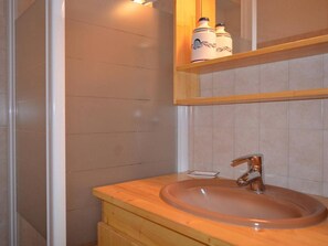 A bathroom with a wooden vanity, a sink, and a mirror above it. There are two containers on the shelf above the mirror.