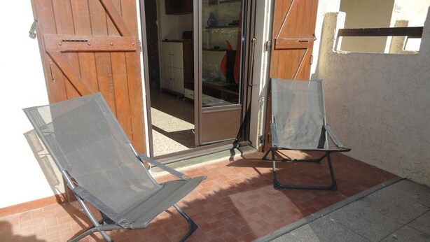 Two outdoor chairs near a sliding glass door, with a tiled patio and a white wall in the background. - Cozy 2-Room Apartment, 300m from Beach with Terraces & A/C, Sleeps 4 (Port-la-Nouvelle)