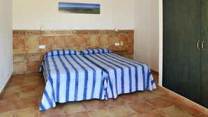 Ein Schlafzimmer mit Bett, Deckenventilator, einem Bild an der Wand und einem Kleiderschrank.